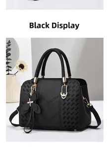 Detail of black pebbled leather handbag with V-shaped stitching and gold metal hardware