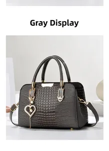 Detail of grey crocodile pattern handbag with gold hardware and pearl heart charm