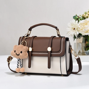 Sac à main bicolore en cuir avec poignée et breloque nuage sur fond minimaliste chic
