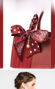 Close-up of deep red leather handbag with polka dot silk scarf and pearl pendant