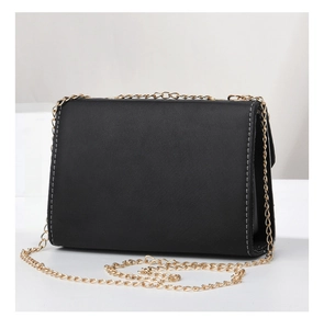 Detail view of black crossbody bag featuring contrast white stitching and gold chain