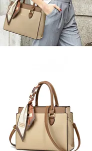 Detail of two-tone beige leather tote with brown handles and elegant silk scarf accessory