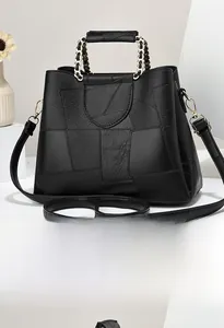 Rear view of black geometric faux leather handbag with gold chain handle and strap