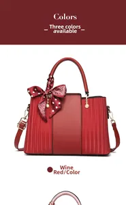 Detail view of wine red handbag featuring polka dot scarf and pearl charms on the handle