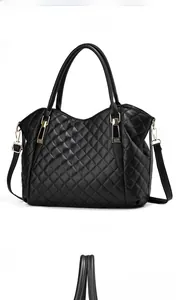 Detail view of black quilted leather tote bag with gold zippers and dual handles