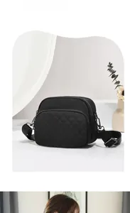 Detail of black quilted nylon crossbody bag with multi-layer zippers and wide strap