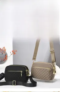 Detail of quilted nylon crossbody bags with multiple zippers and golden hardware