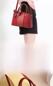 Macro detail of red tote bag featuring vertical pleated texture and pearl charm accent
