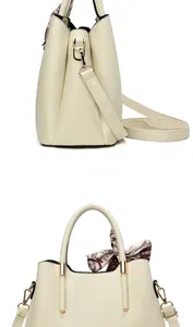 Detail view of beige pebbled leather handbag with silk scarf and gold hardware accents
