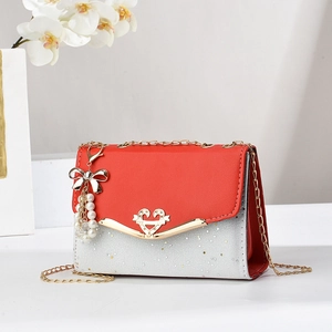 Quilted red and silver sequin chain bag with heart buckle and pearl bow charm on white desk