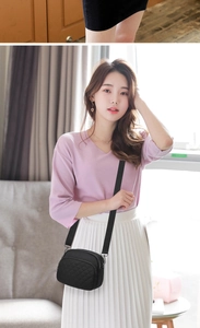 Detailed view of black quilted crossbody bag with three zipper compartments worn by model