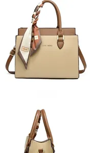 Detail of beige and brown tote bag with decorative scarf handle and gold logo