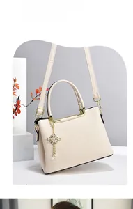 Dettaglio ravvicinato della borsa a mano in ecopelle color crema con hardware dorato