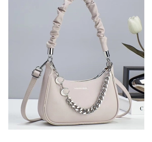 Beige litchi grain crescent bag featuring a decorative moon charm chain and handle