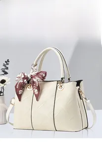 Détail du sac en cuir blanc crème avec texture géométrique et poignée en foulard de soie