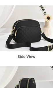 Close-up of black quilted nylon bag showing three zippered compartments and gold hardware