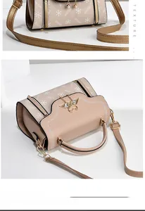 Detail of cream leather handbag with gold butterfly charm and embossed brand lettering