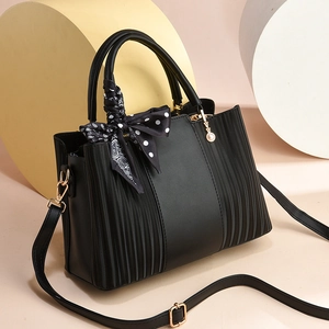 Elegant black leather handbag with pleated details, silk scarf, and pearl charm pendant