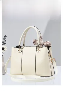 Détail du sac à main crème avec anneaux métalliques et foulard décoratif imprimé