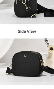 Detailed side view of black nylon crossbody bag with dual golden zippers and strap