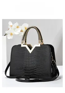 Détail du sac à main noir motif crocodile avec métal en V doré et poignée tressée