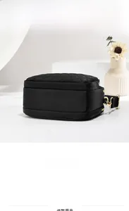 Detail view of black quilted crossbody bag with gold hardware and side structure