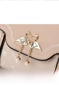 Detail of pink leather bag featuring gold swan hardware with heart crystal and pearls