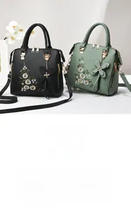 Detailed view of floral embroidery and butterfly pendant on leather handbags