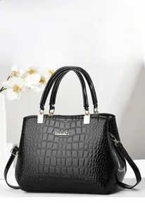 Detail of black crocodile texture tote bag with golden metal logo and shiny PU leather finish