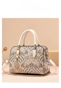 Detailed view of jacquard pattern handbag with gold hardware and leaf pearl charm