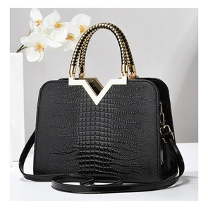 Détail d'un sac à main en cuir crocodile avec ferrures dorées et poignée tressée
