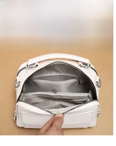 Detailansicht der elfenbeinfarbenen Ledertasche mit vielen Fächern und Reißverschlüssen