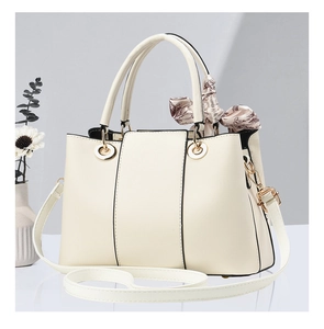 Détail d'un sac à main beige avec boucles dorées, bandoulière amovible et foulard en soie