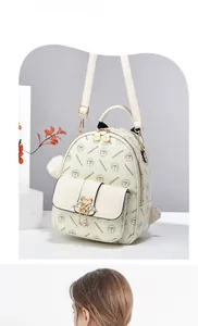 Detail of cream backpack with gold swan buckle, heart zipper and plush ball charm