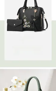 Detail of black pebbled leather tote set with floral embroidery and butterfly charm