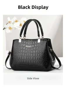 Side view of black crocodile pattern leather handbag with gold metal logo and handle