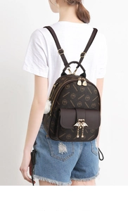 Detail of vintage brown backpack with letter print, swan charm, and pearl tassel
