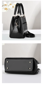 Detail view of black crocodile pattern handbag with gold hardware and protective base studs