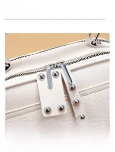 Detailansicht der weißen Handtasche mit Lychee-Muster und silbernen Doppel-Reißverschlüssen