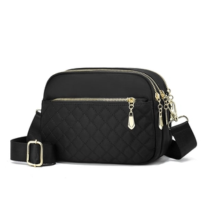 Black quilted nylon crossbody bag with multiple gold zippers and adjustable strap
