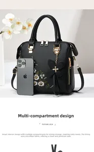 Detailed embroidery on a black leather handbag with gold zippers and floral charm