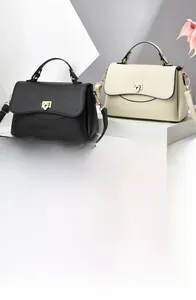 Detail of soft leather crossbody bags in black and cream white with metal shield buckles