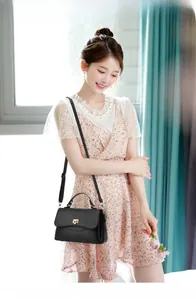 Close-up of black lychee-textured crossbody bag with golden buckle and adjustable strap