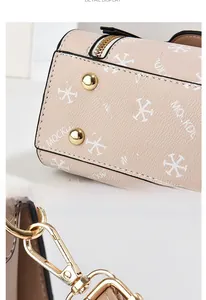 Detailed view of beige faux leather bag showing gold bottom studs and metal hooks