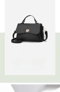 Detail view of black lychee grain leather crossbody bag with golden metal shield lock