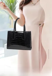 Detailed close-up showing the glossy crocodile texture and premium finish of the black tote bag