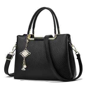 Chic black pebbled leather handbag with gold hardware, pom-pom charm and crossbody strap