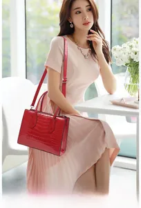 Detail of red crocodile textured tote with glossy finish and premium metal hardware