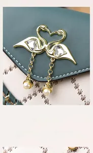 Detail of golden swan magnetic clasp with crystal and pearl on green and white leather bag