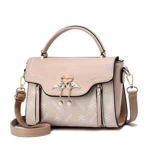 Pink crossbody bag with gold swan buckle, pearl pendant, and lettered pattern print